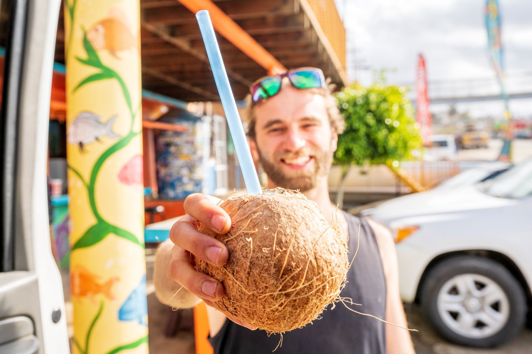 Smiling man holding a coconut toward the camera